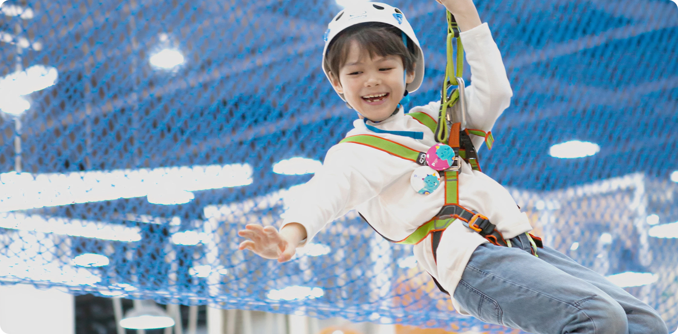 어린이가 헬멧쓰고 짚라인을 즐기는 모습