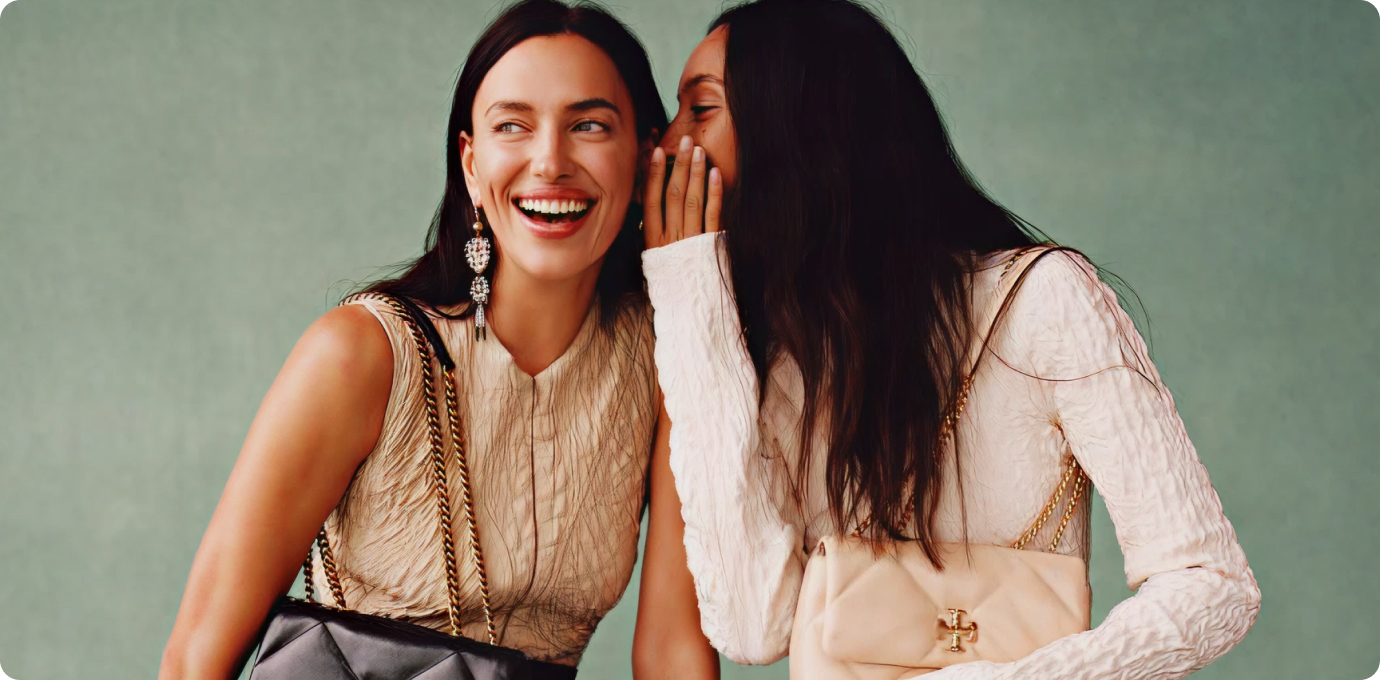 젊은 두 여성이 토리버치 가방을 들고 귓속말을 하는 모습